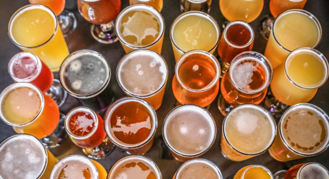 A birds eye view of a table with beer glasses with different coloured beer on it