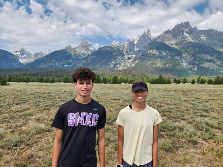 Two people standing in a field with mountains in the background
AI-generated content may be incorrect. Two people standing in a field with mountains in the background
AI-generated content may be incorrect.