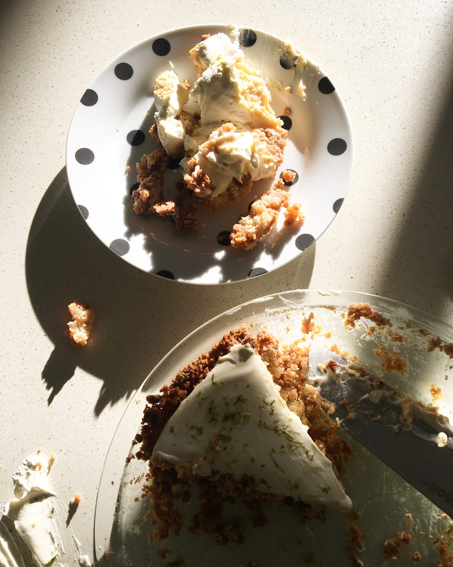Key lime pie slice in a pie dish with a plate featuring a slice that was dropped them reassembled to serve.