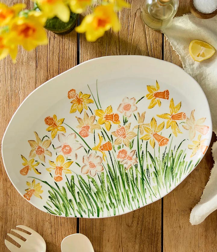 Pink tea towels, a daffodil serving platter, ceramic berry bowls, and a scalloped wooden cutting board.