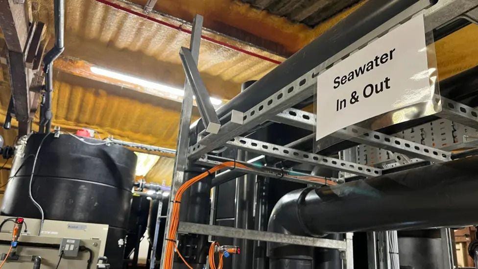 a lot of pipes and tanks with a sign saying 'seawater in and out'.