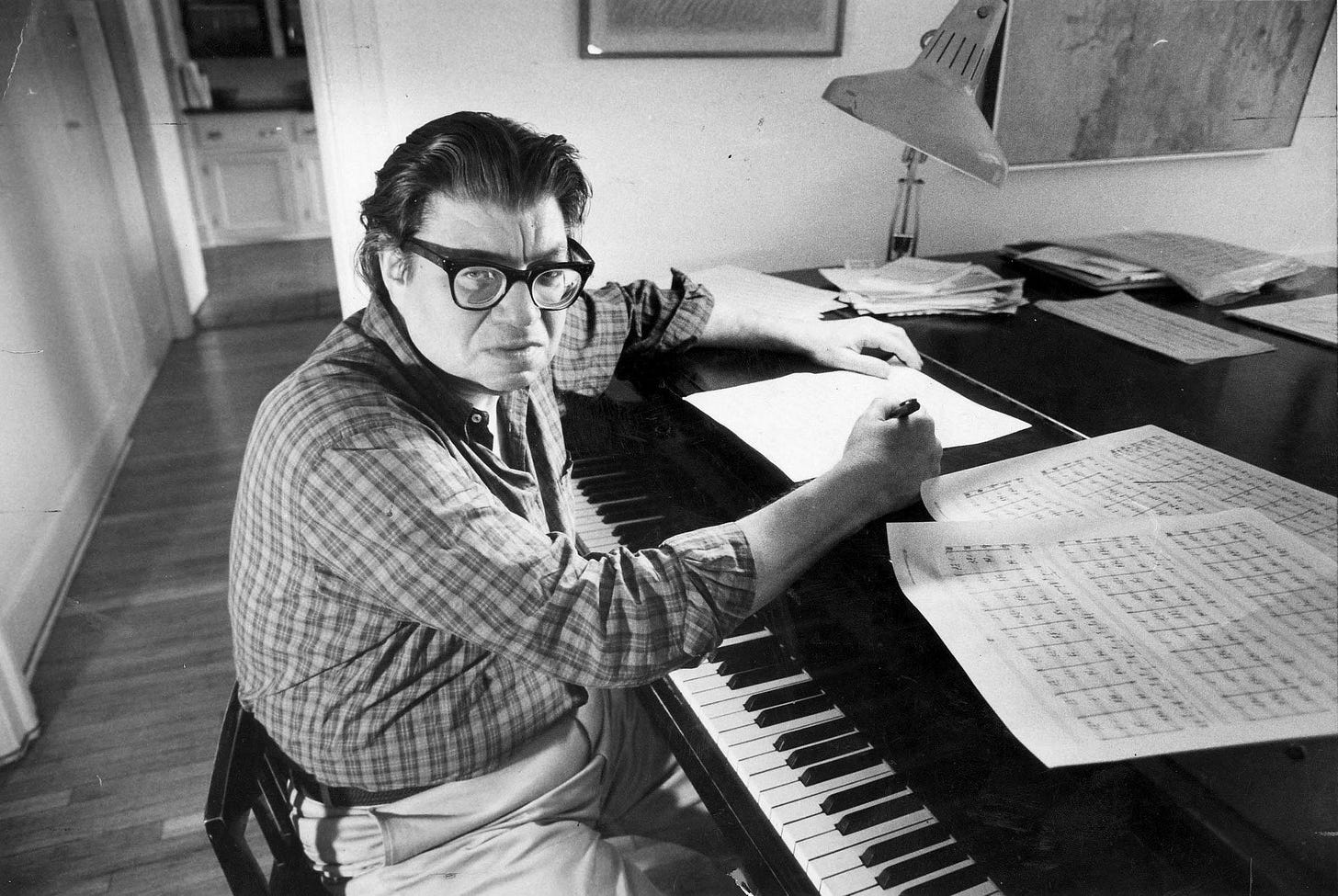 A person sitting at a piano writing on paper

Description automatically generated