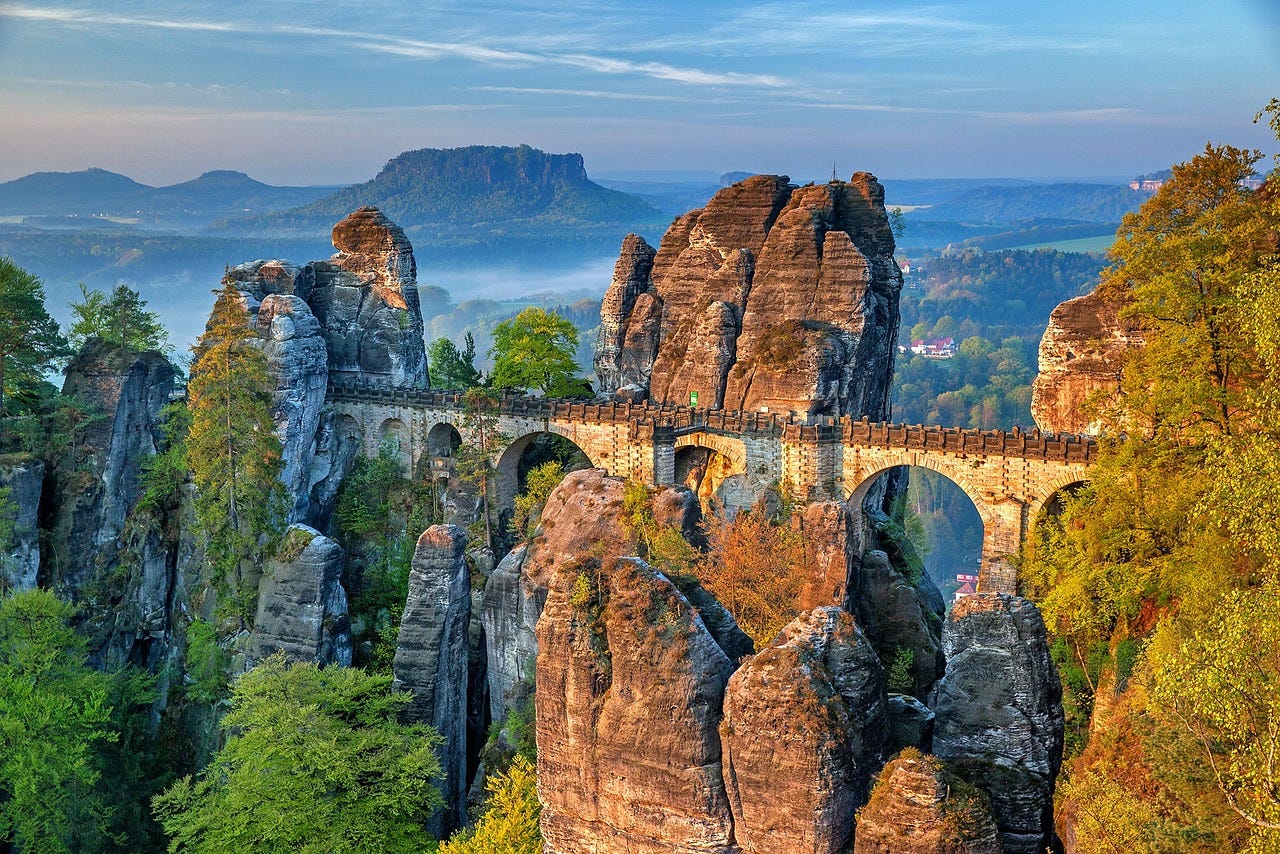 A photo of mountains and rock formations, with the Bastei Bridge connecting tall rock formations