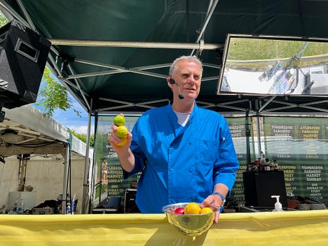 Three images of a man dressed in a blue shirt at a food festival standing on a stage squeezing a lemon