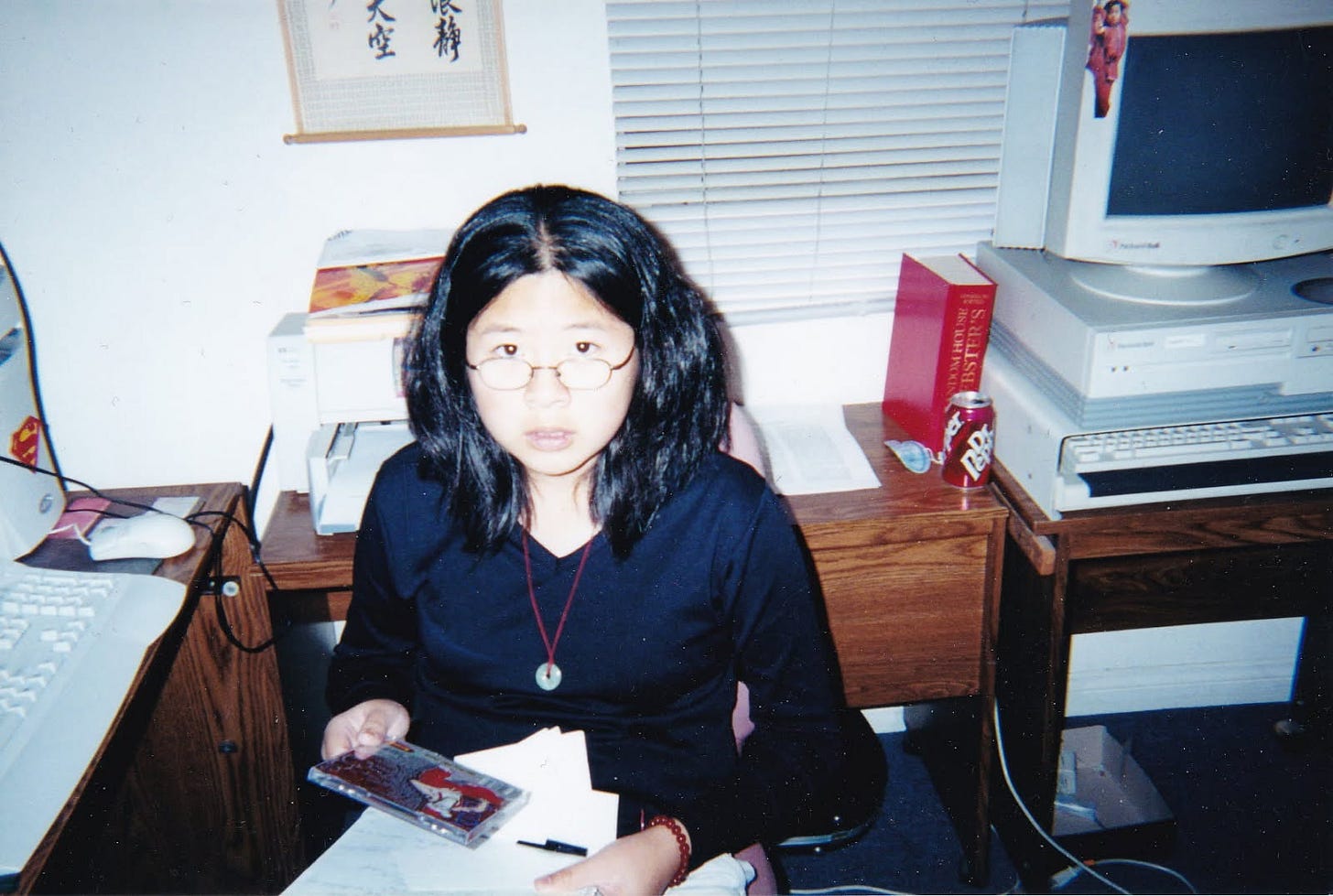 Photo of Asian teenaged girl with glasses, sitting in front of a computer and holding a CD Photo of Asian teenaged girl with glasses, sitting in front of a computer and holding a CD