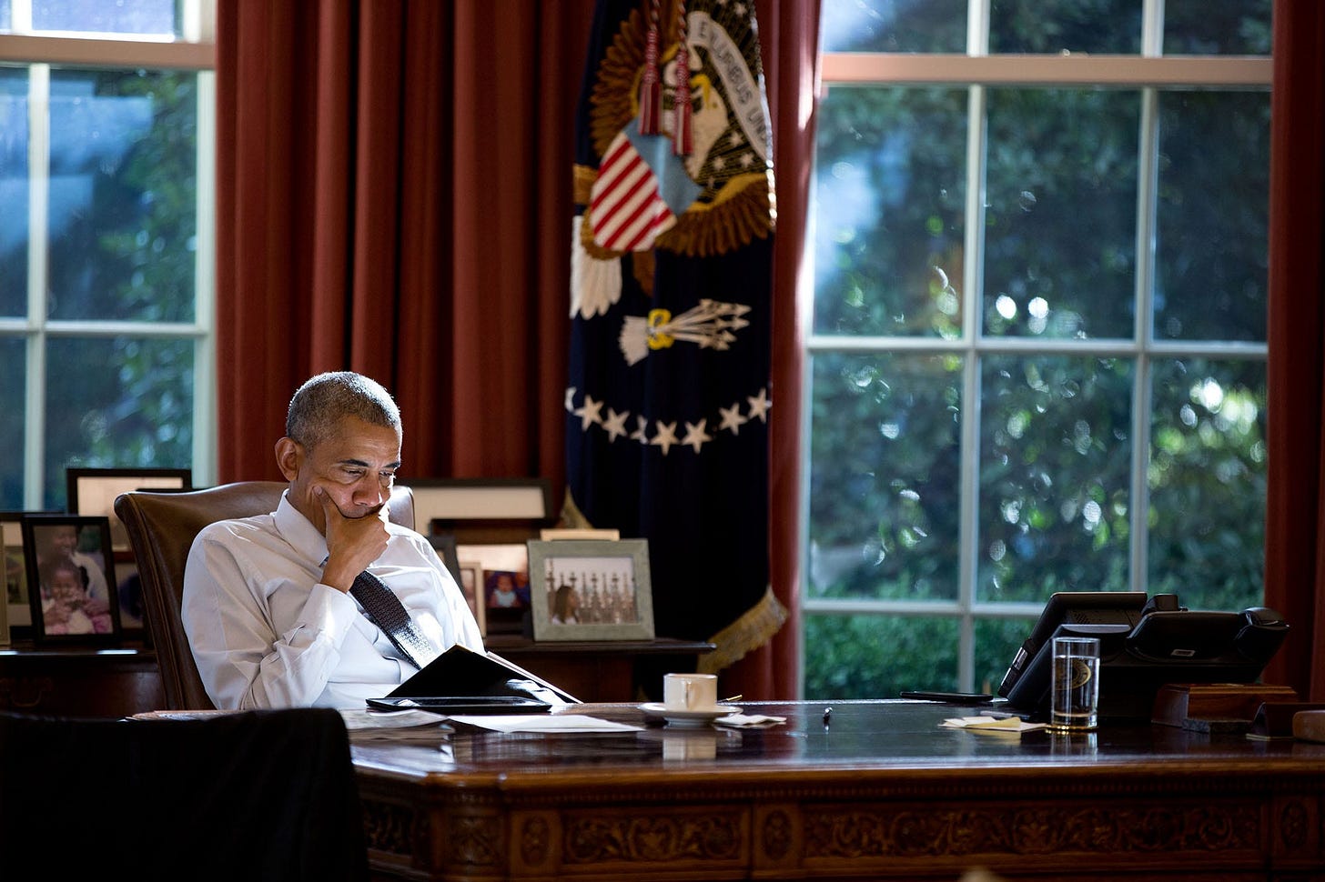 October 14, 2016: Golden afternoon light beautifully backlights President Obama working diligently at the Resolute Desk in the Oval Office, a serene scene of leadership. October 14, 2016: Golden afternoon light beautifully backlights President Obama working diligently at the Resolute Desk in the Oval Office, a serene scene of leadership.