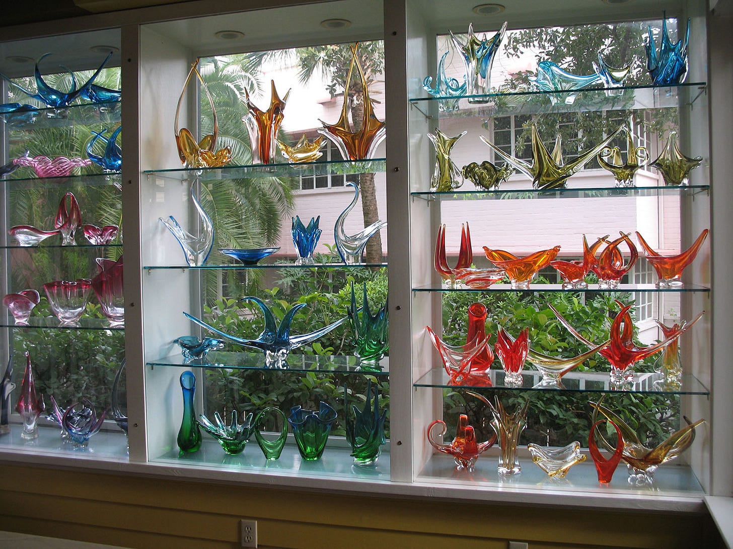 art glass displayed on glass shelves in a window