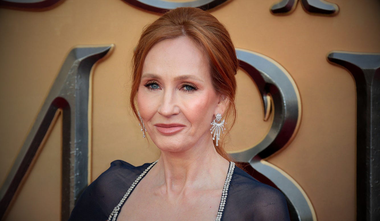 Red-haired woman (Rowling) in a black dress and statement earrings at an awards event