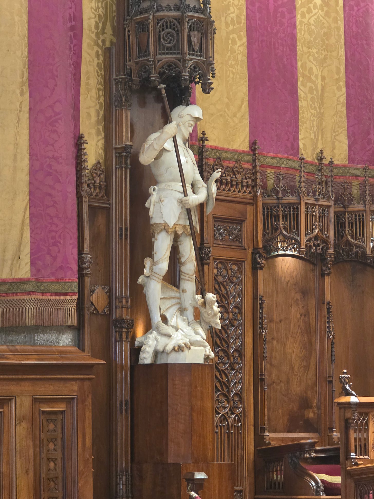Estatua de mármol blanco de Sant Jordi con armadura y el dragón a sus pies en el Salón del Consell de Cent del Ayuntamiento de Barcelona