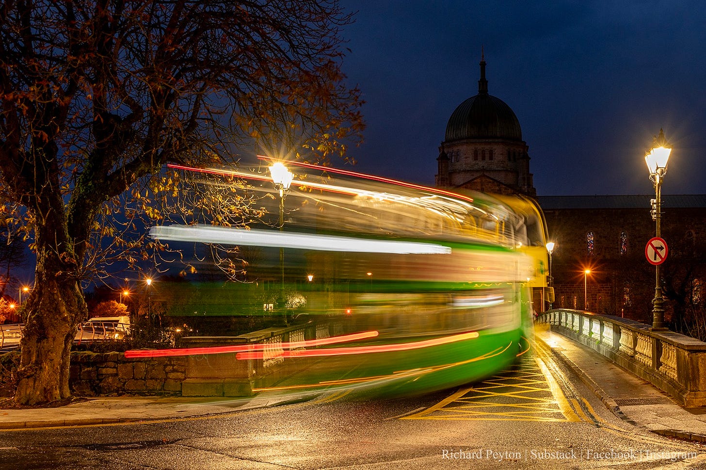 A slow shutter speed photo of a bus going over the Salmon Weir towards the Galway Cathedral in the early hours.