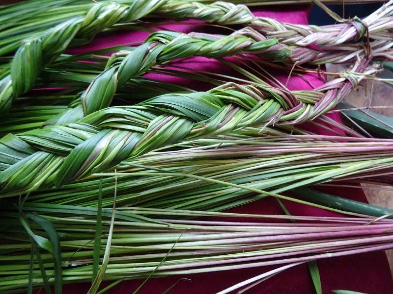 A handful of both braided and individual clumps of sweetgrass on a table.