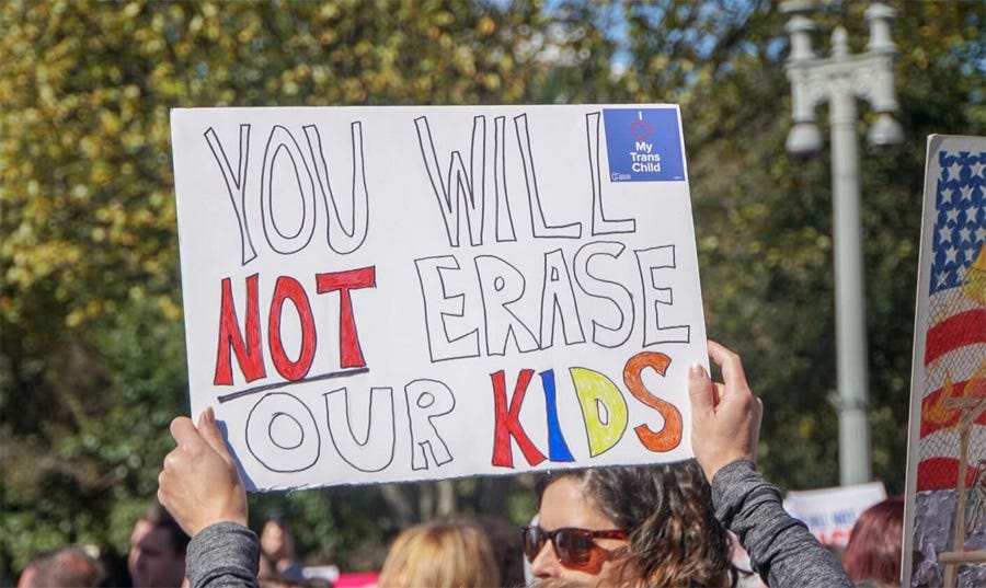 Photo of a handmade sign reading 'You will NOT erase our kids!' Photo of a handmade sign reading 'You will NOT erase our kids!'