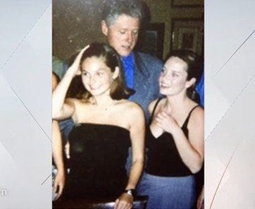 Former President Bill Clinton at a social gathering with two women, one in a black dress and the other in a light-colored top, smiling and engaging in conversation.