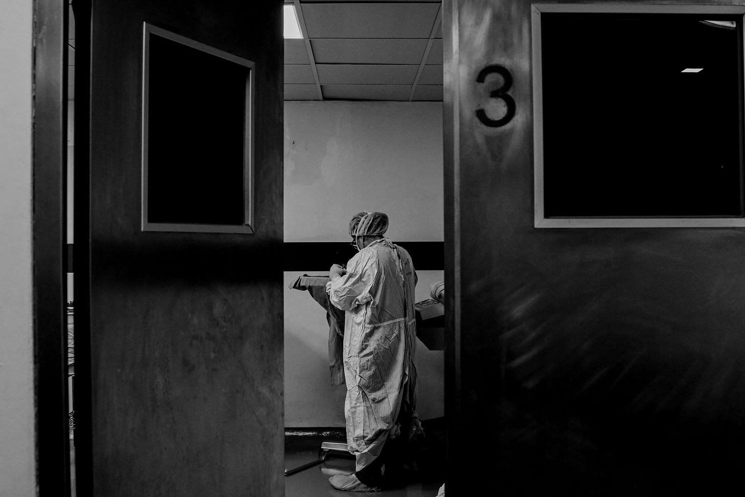 man in white and blue robe standing near white wooden door