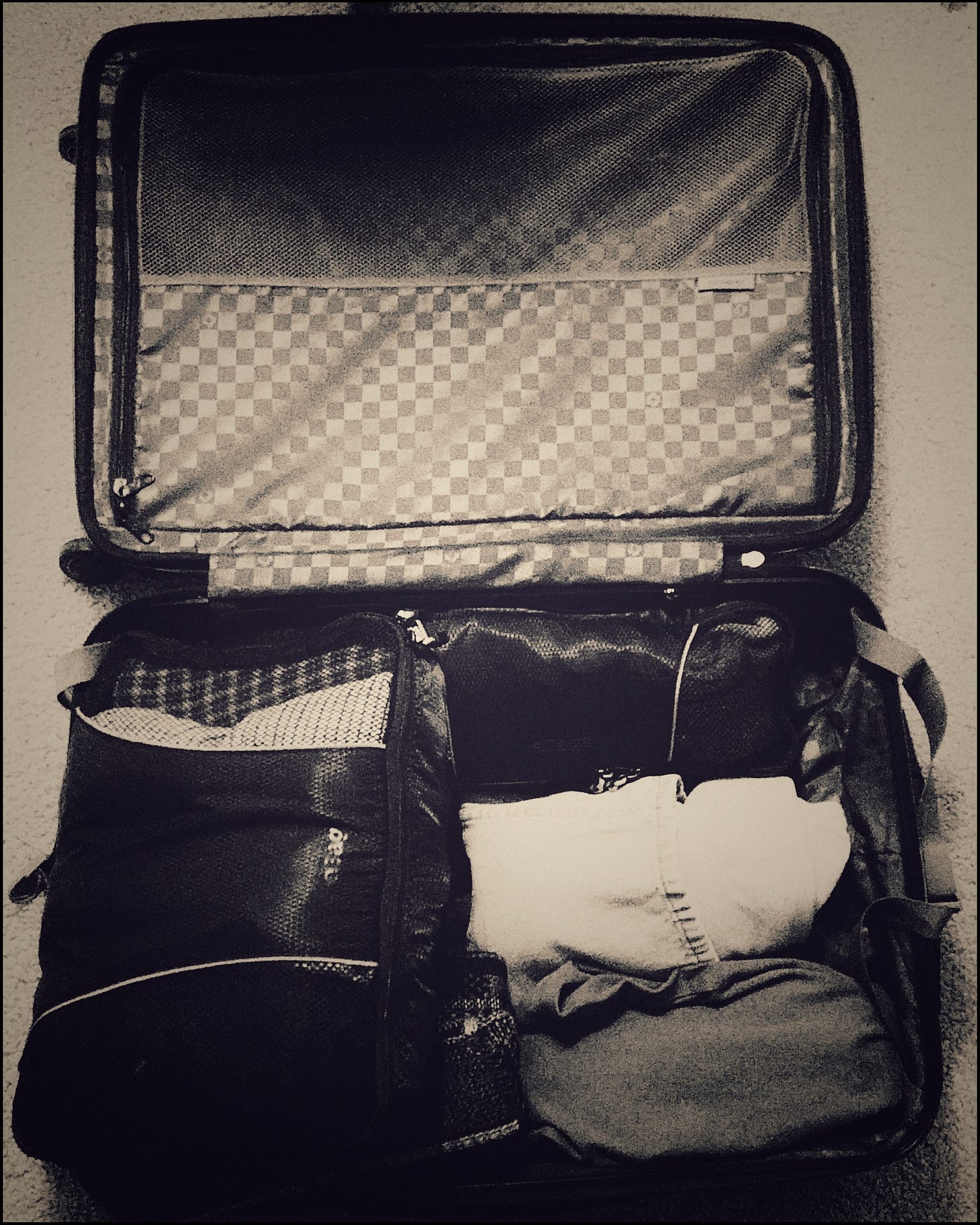 An open suitcase, almost completely packed for travel...