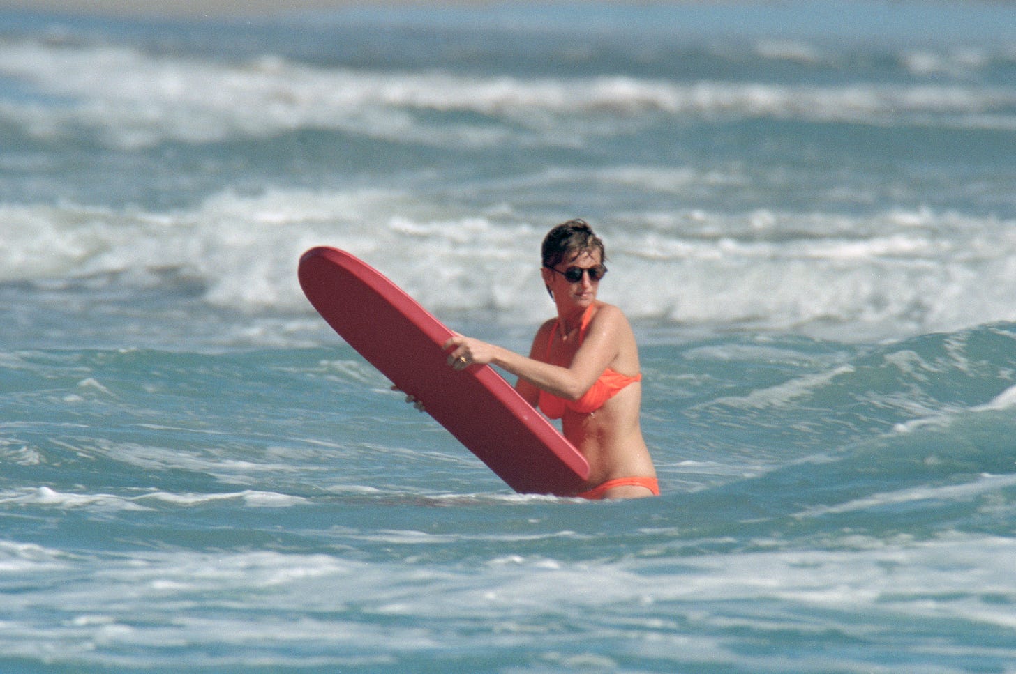 Princess Diana in the sea holding a surfboard