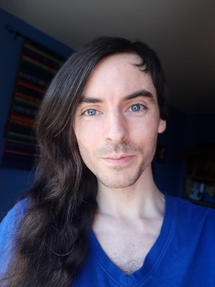 Portrait photo of me. Asymmetrical haircut, long dark brown on one side, short on the other. Large blue eyes. Pale skin. Blue shirt. Portrait photo of me. Asymmetrical haircut, long dark brown on one side, short on the other. Large blue eyes. Pale skin. Blue shirt.