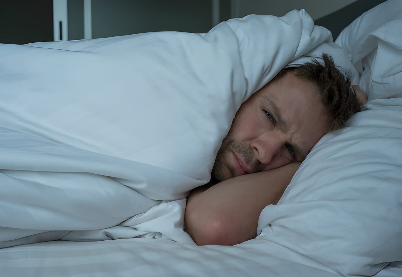 Man lying in bed looking unhappy Man lying in bed looking unhappy