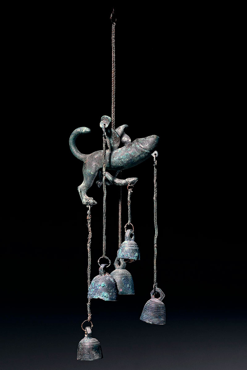 A winged penis with legs and a tail, and bells hanging from it A winged penis with legs and a tail, and bells hanging from it