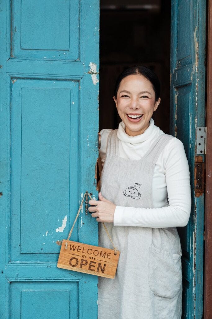 photo of woman smiling while standing on doorway