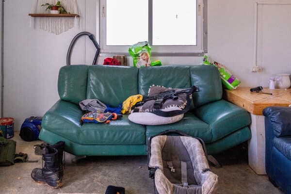 A couch with a gun on top of a pillow next to a baby carriage.