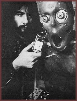  Behind-the-scenes black and white photograph: Rob Bottin poses with the Palmer-Thing animatronic puppet from The Thing (1982), showing the creature's exposed mechanical skull and wide eyes.