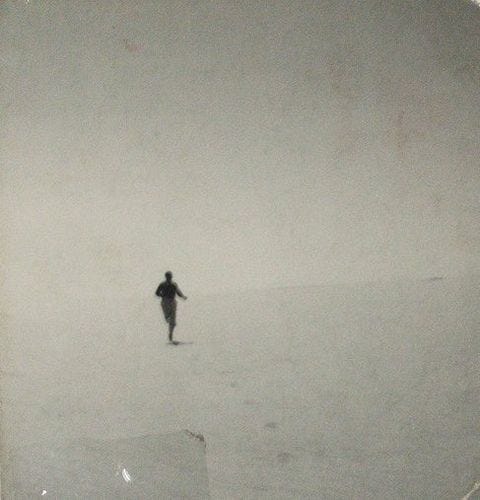 This may contain: a person is walking in the snow on a foggy day