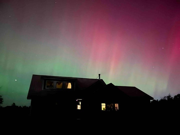 Pink and green lights over a black landscape.