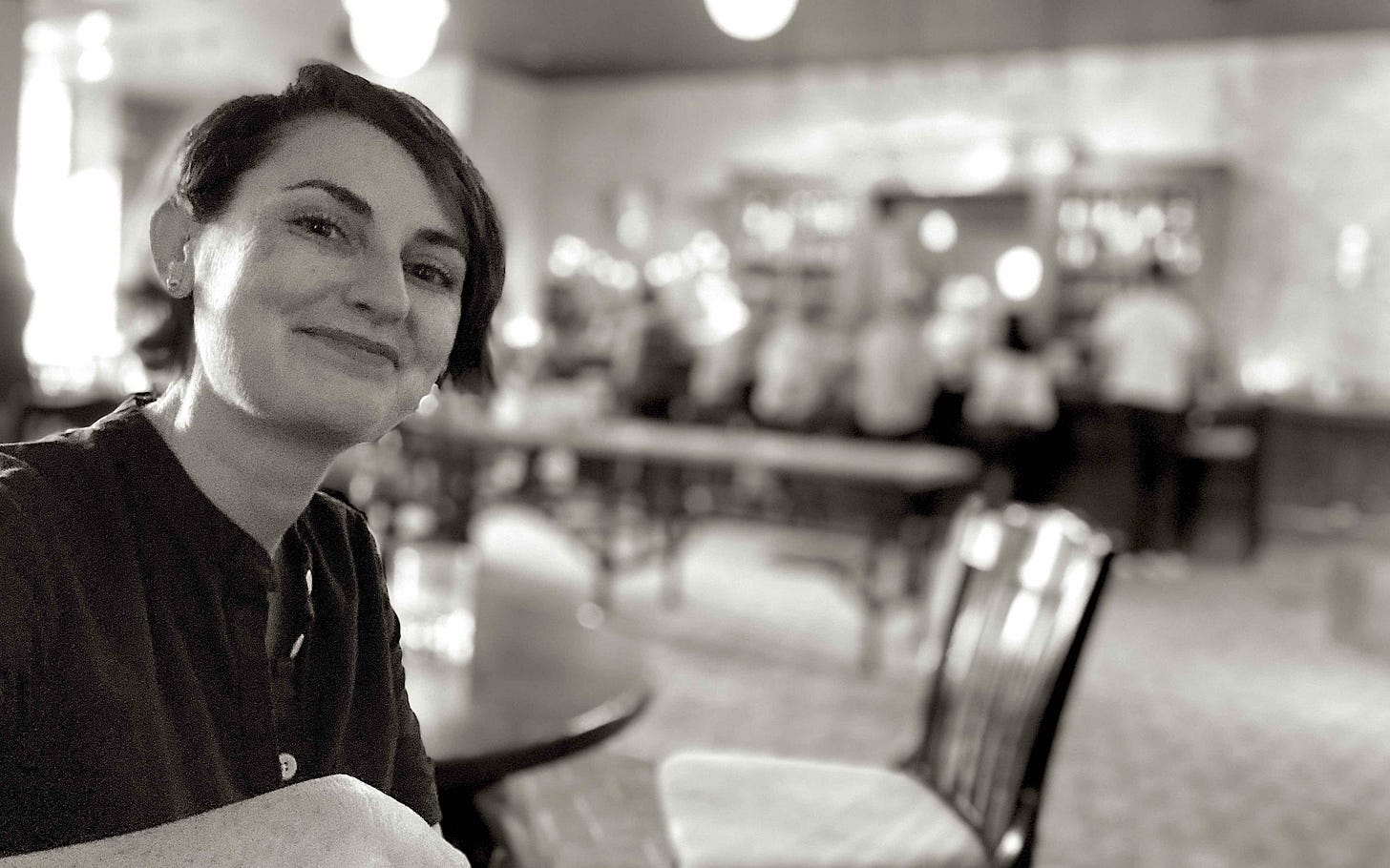 woman at indoor table with bar in background