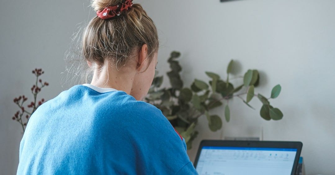 woman in blue sweater sitting in front of laptop computer