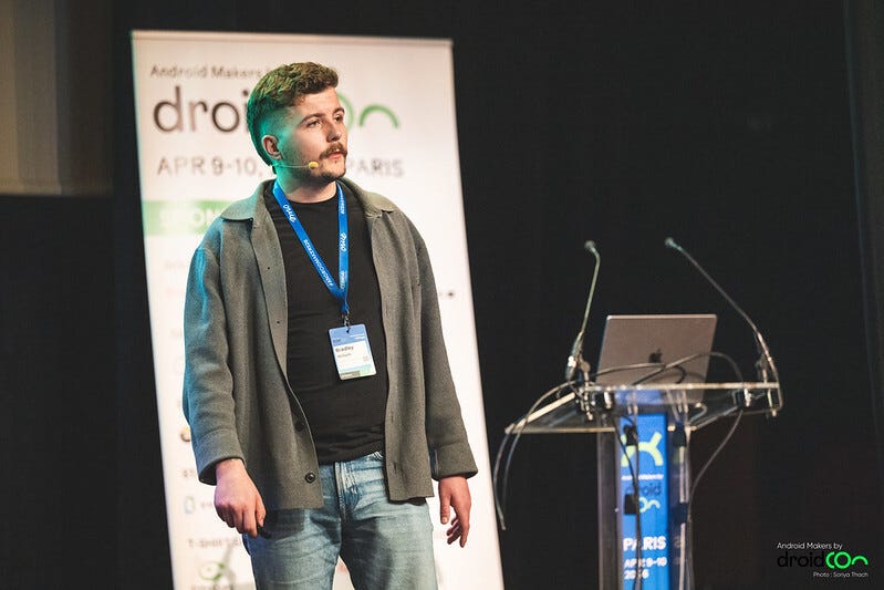 Me on the stage speaking to the crowd with a laptop and screen in the background