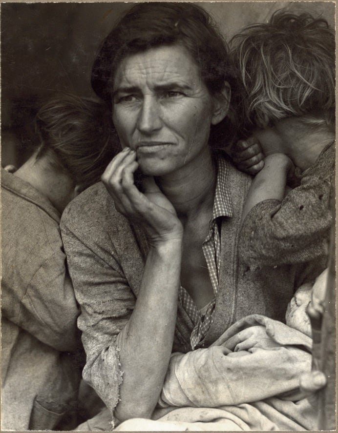 Mother of seven, nestles a baby and two older children. Her brow is furrowed with worry.