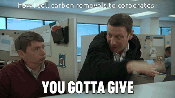 Animated GIF captioned "how I sell carbon removals to corporates". In an open-plan office, a man in a dark jacket leans over a seated coworker in a maroon sweater and jabs a finger at him, with the caption "YOU GOTTA GIVE".