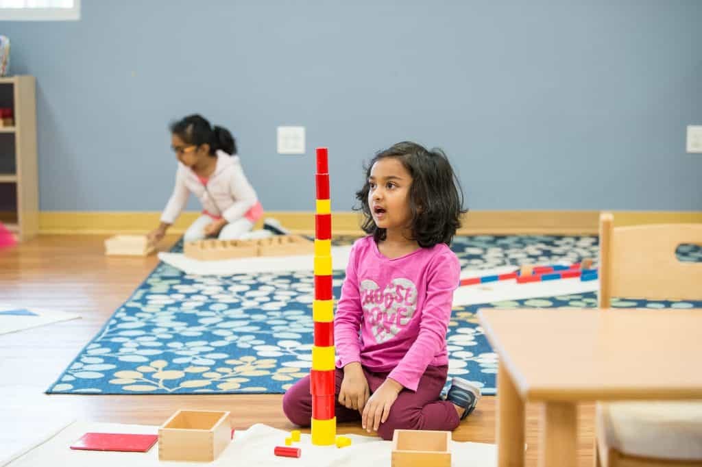 Girl building Montessori color tower showing hands-on AI learning benefits for ages 0-6