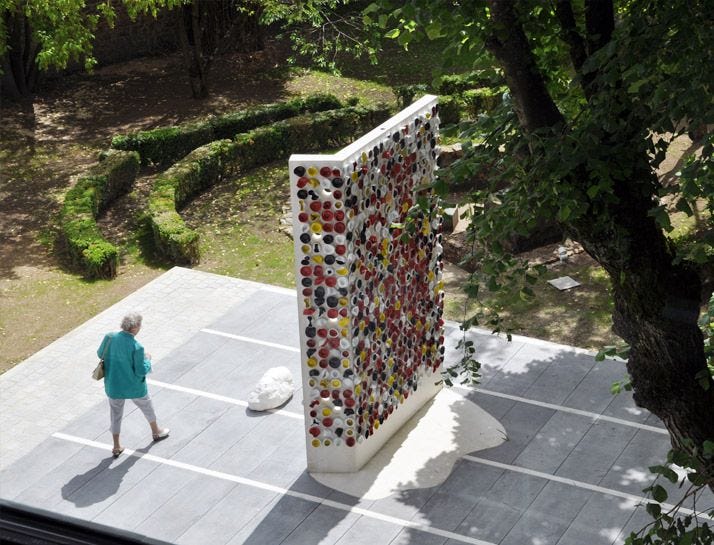 This may contain: an aerial view of a woman walking past a sculpture in the middle of a park