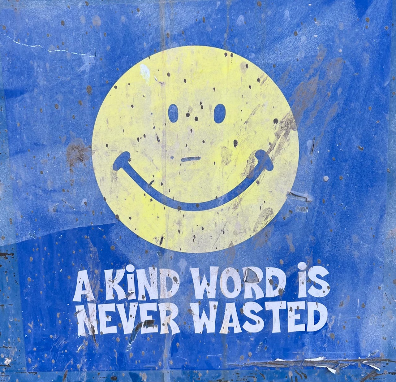 Graffiti image of a smiley face that says "a kind word is never wasted"