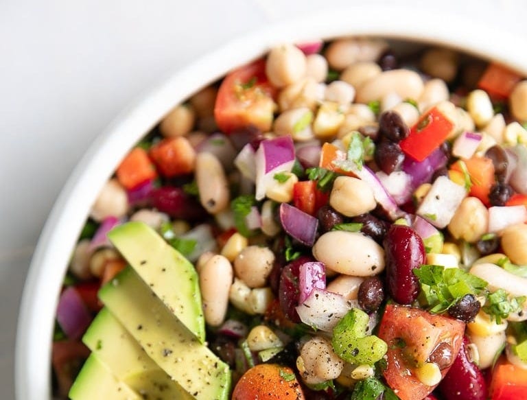 Overhead image of loaded Mexican bean salad topped with sliced avocado.