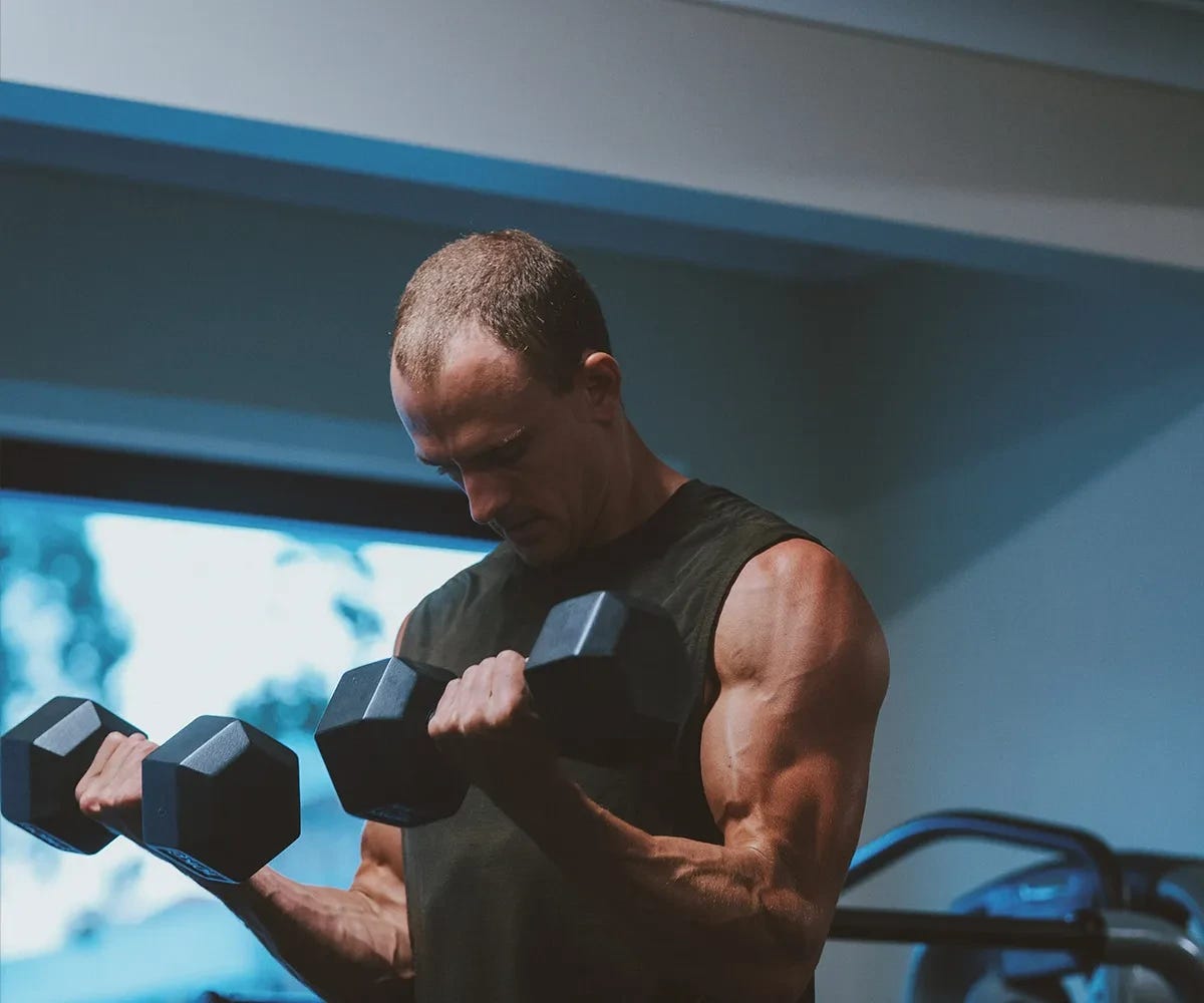 Muscular man performing dumbbell bicep curls. Muscular man performing dumbbell bicep curls.