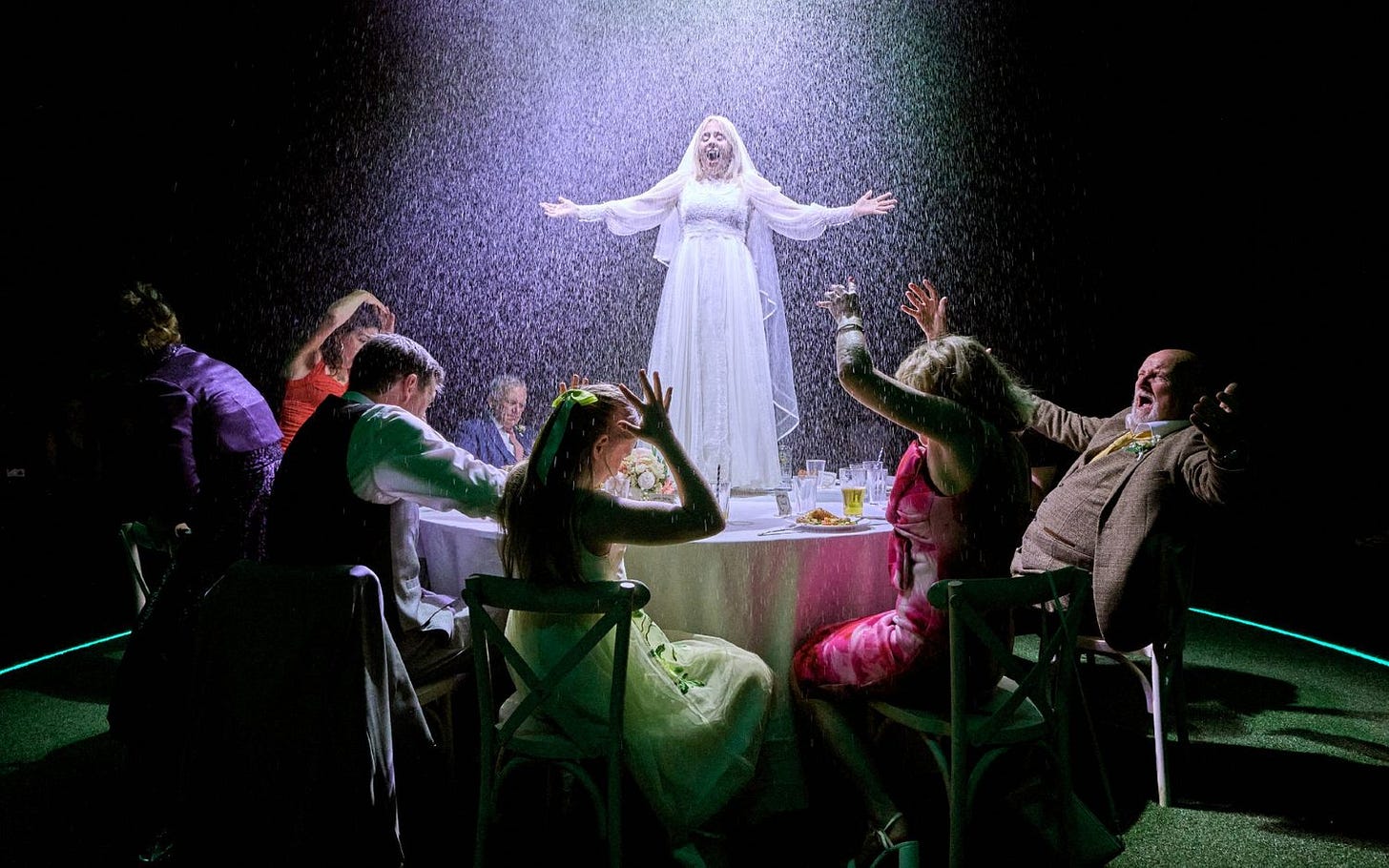 A bride stands on a table as rain starts to fall and the wedding guests run for cover.