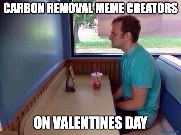 A man sitting alone in a diner booth with a drink. Top: "Carbon removal meme creators." Bottom: "On Valentine's Day."
