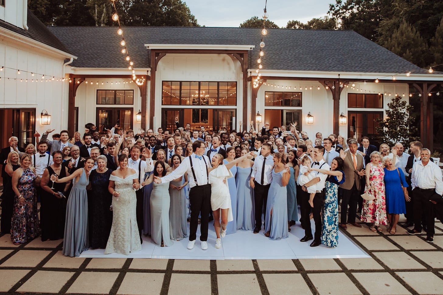 a wedding full of people on the dance floor under the string lights a wedding full of people on the dance floor under the string lights