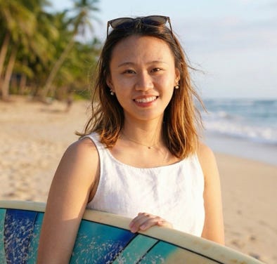 Meng Lei holding a surfboard on the beach