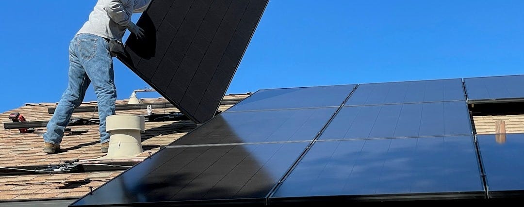 man in white dress shirt and blue denim jeans sitting on white and black solar panel man in white dress shirt and blue denim jeans sitting on white and black solar panel