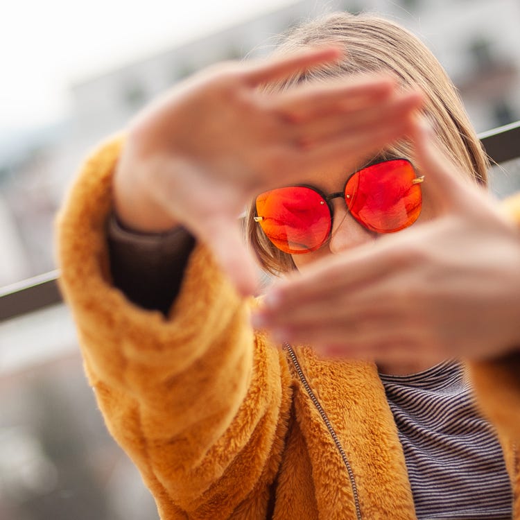 Woman framing her face with her fingers for viewpoint perspective.