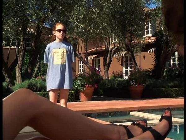 This may contain: a woman standing next to a pool with her feet on the ground and wearing sandals
