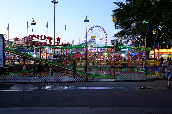 Overhead shot of attendees, friends in the gondola behind me on the Skyride, seed art wall at the Crop Art show, attendee looking over loaves of bread, amusement rides, golden hour behind the crowd, Sweet Martha's Cookies at night.