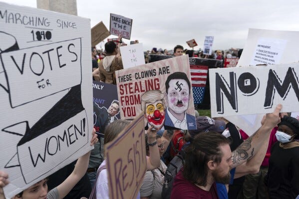 Demonstrators carry signs during the "Hands Off!" protests against President Donald Trump and Elon Musk at the Washington Monument in Washington, Saturday, April 5, 2025. (AP Photo/Jose Luis Magana)