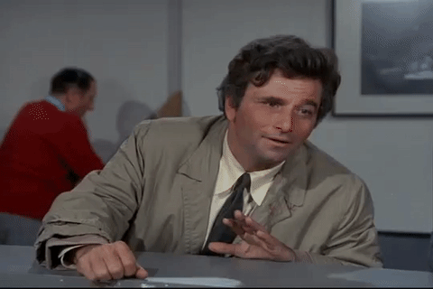 Gif dal telefilm "Colombo", con il tenente Colombo vestito con un trench marroncino mentre si appoggia su un bancone azzurro e si porta una mano alla fronte, grattandosela in segno di pensiero profondo. Dietro sfondo di una parete bianca e persone che camminano.