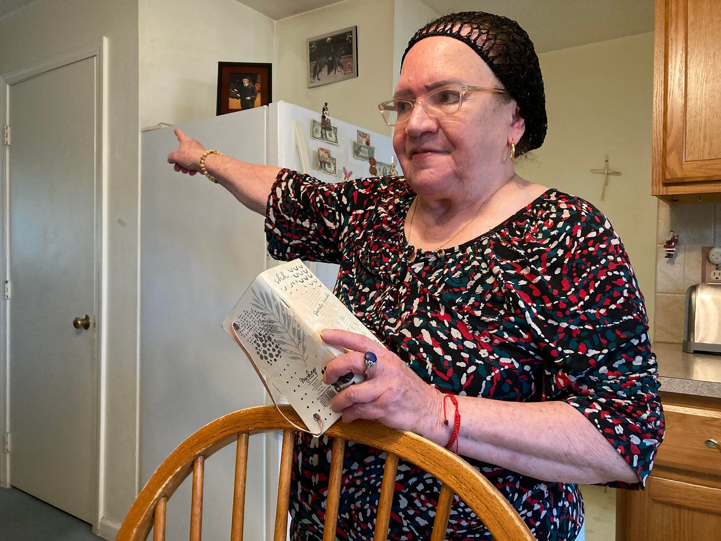 A photo of a woman standing indoor, pointing to a door. A photo of a woman standing indoor, pointing to a door.