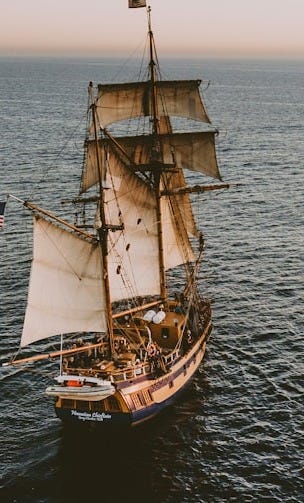 brown sailboat in beach under white sky